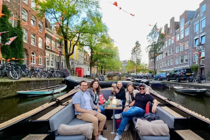 a group of people sitting on an open boat on a small canal in Amsterdam