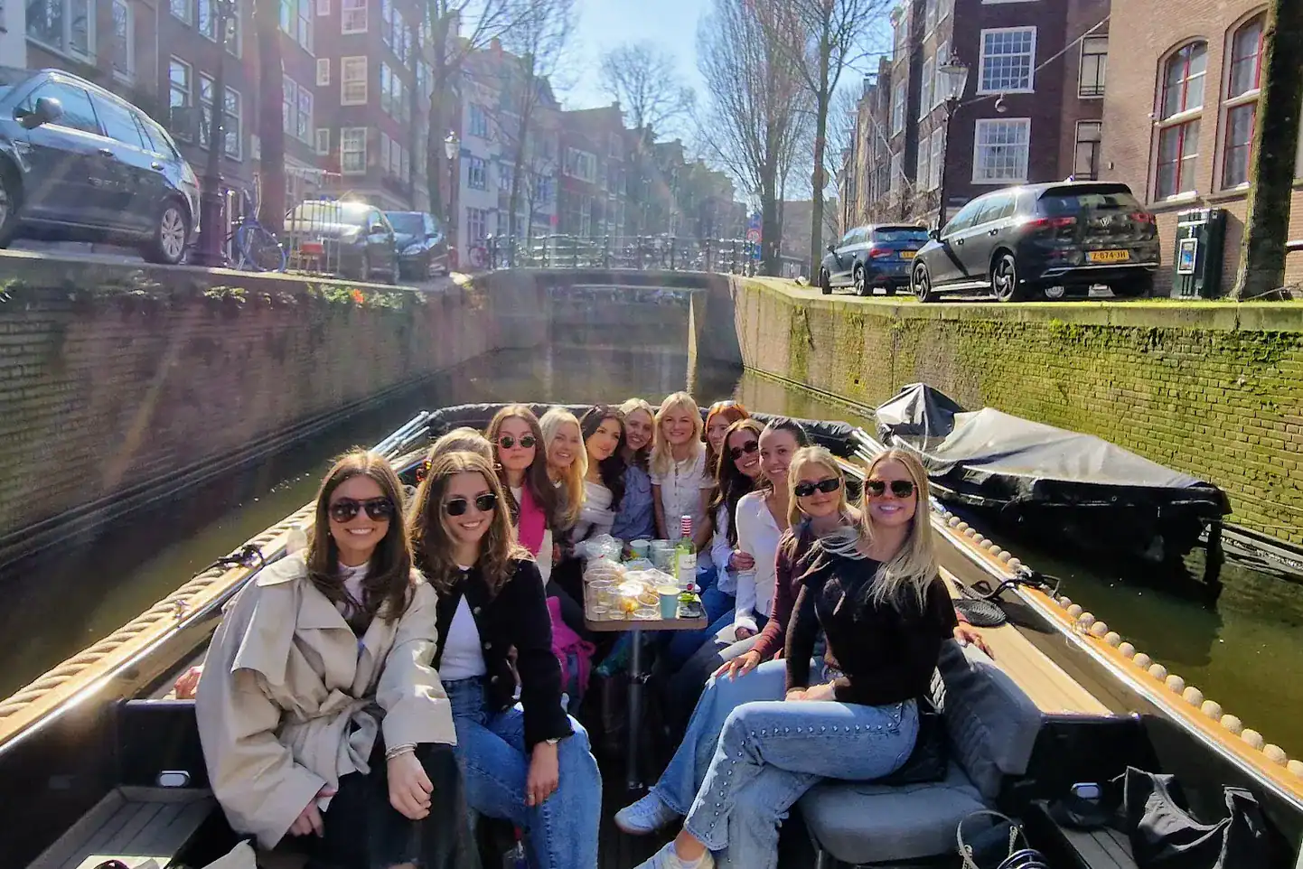 a group of girls on a modern open boat on a small Amsterdam canal