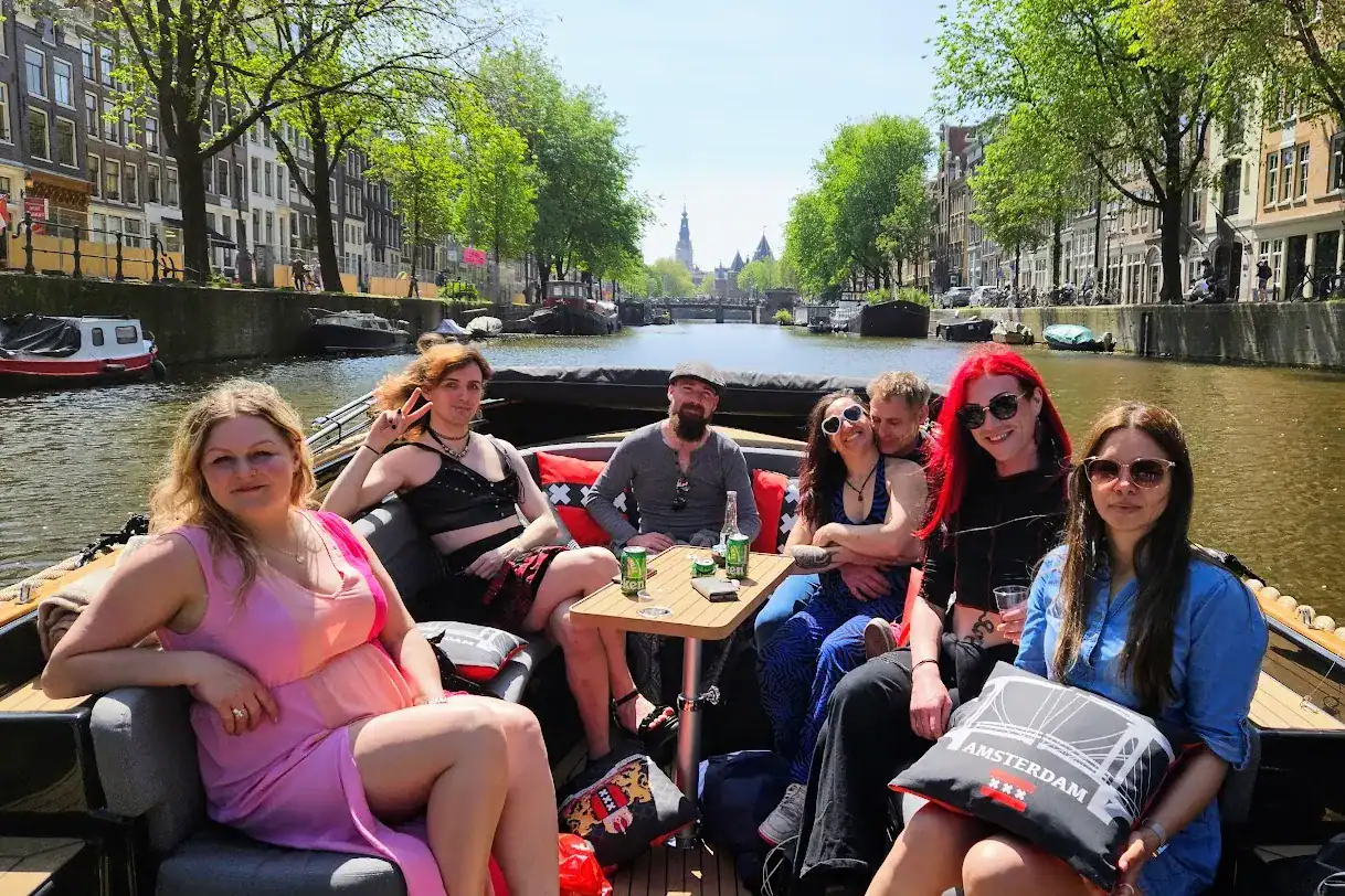 a group of lgbtq people on an open boat in Amsterdam with canal view in the background