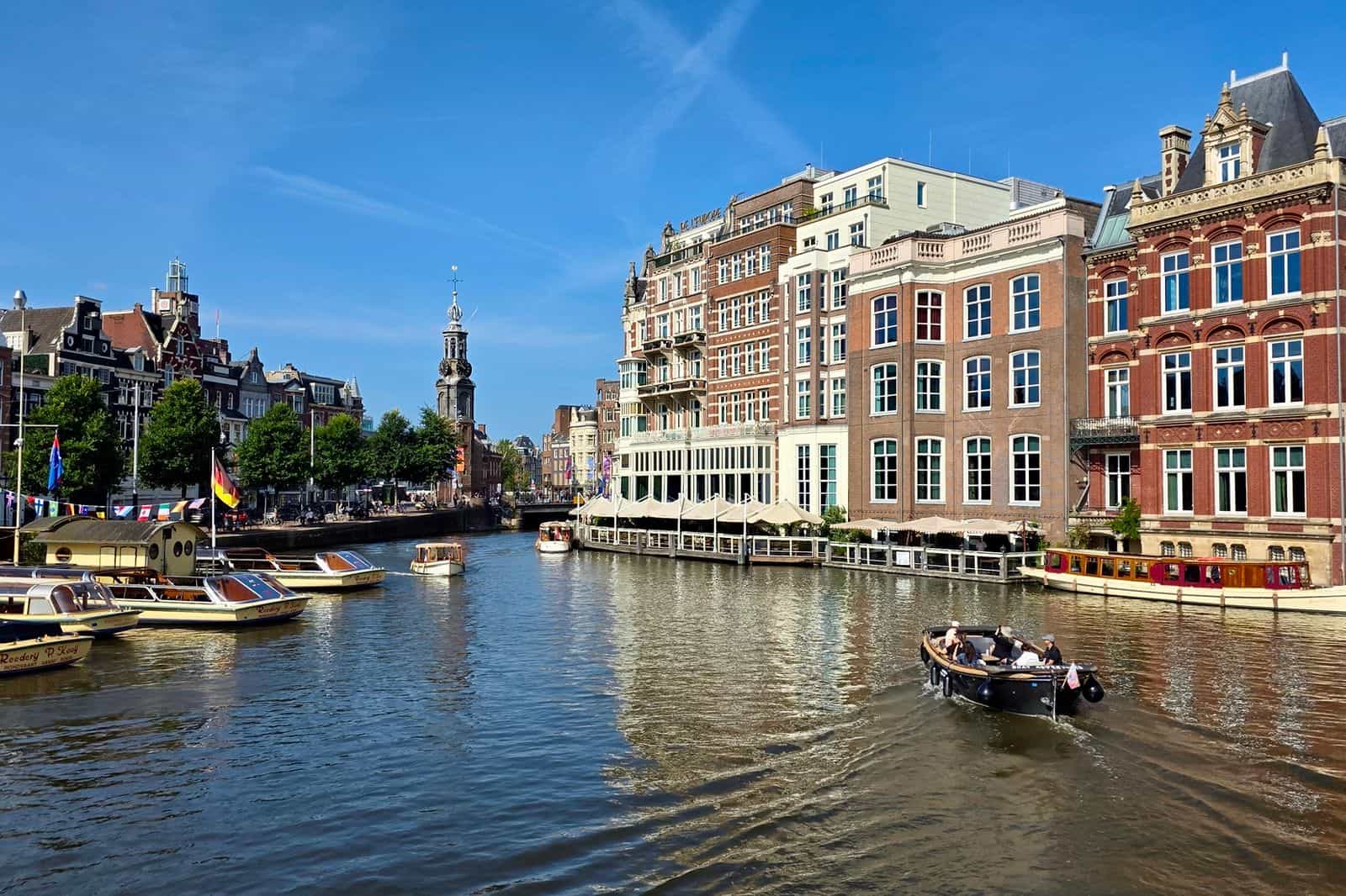 an open boat on the Amstel Rover with the Munt tower and grand Amsterdam buildings in the background