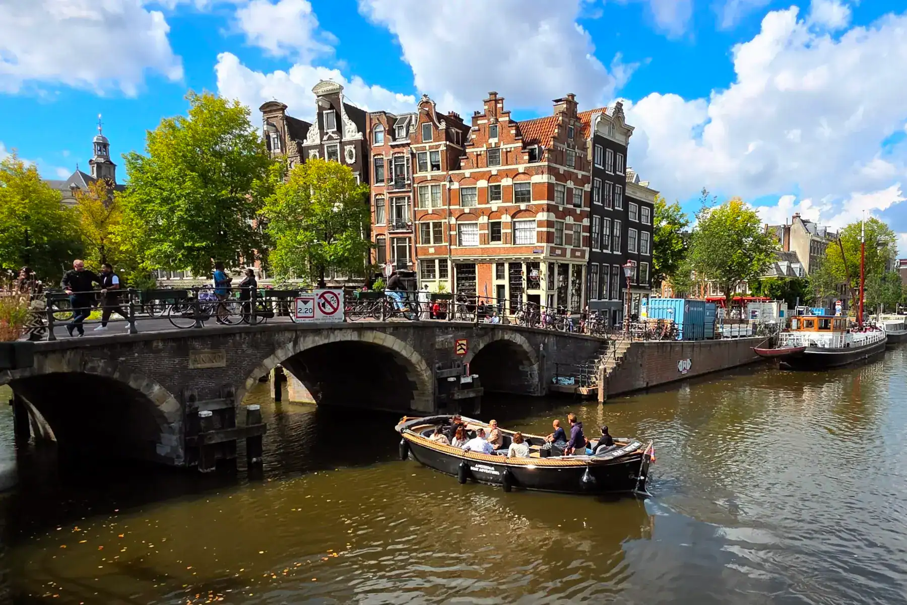 Historic Dutch canal boat tour in Amsterdam with colorful gabled buildings and scenic waterways.