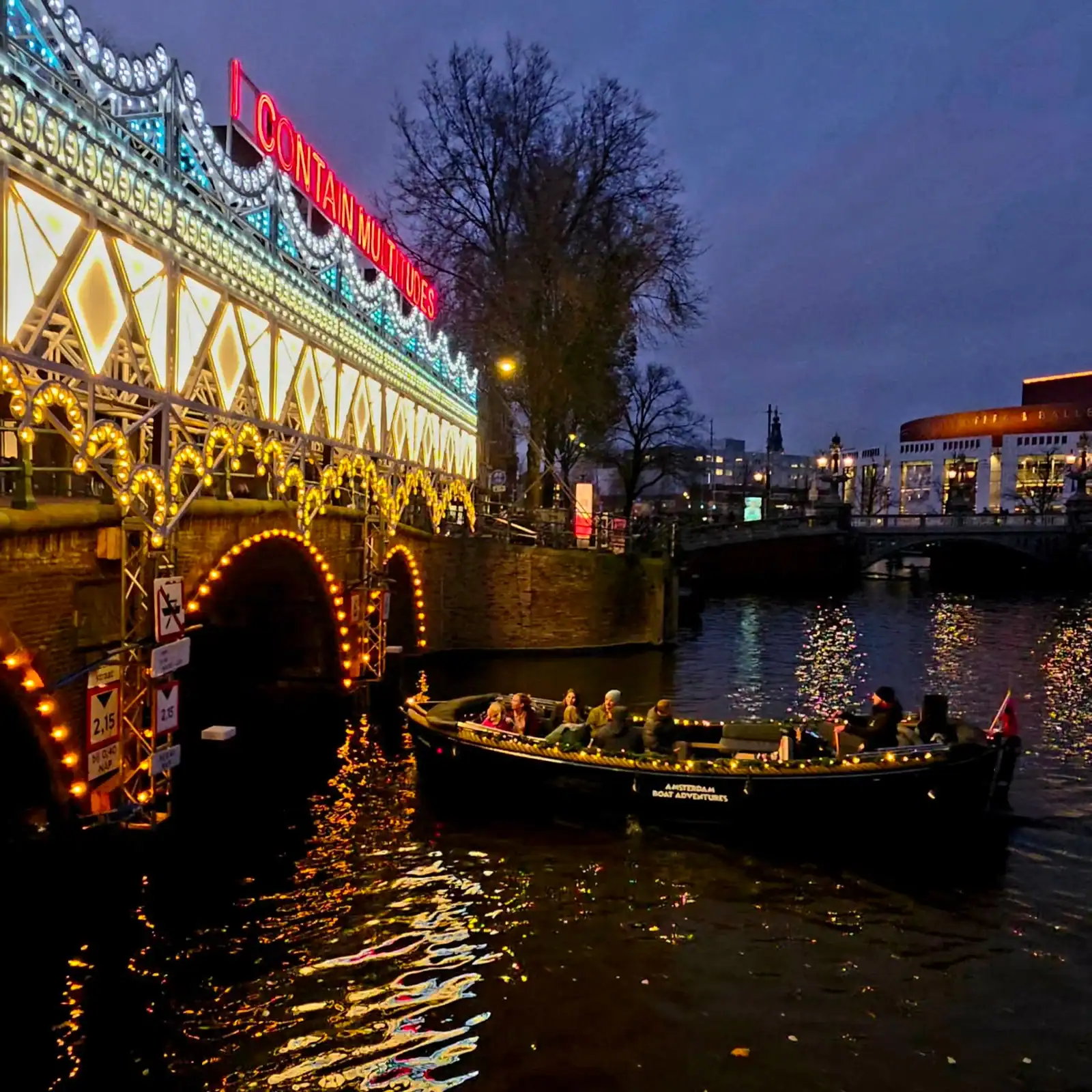 Scenic Amsterdam canal cruise featuring vibrant lights and city views at dusk.
