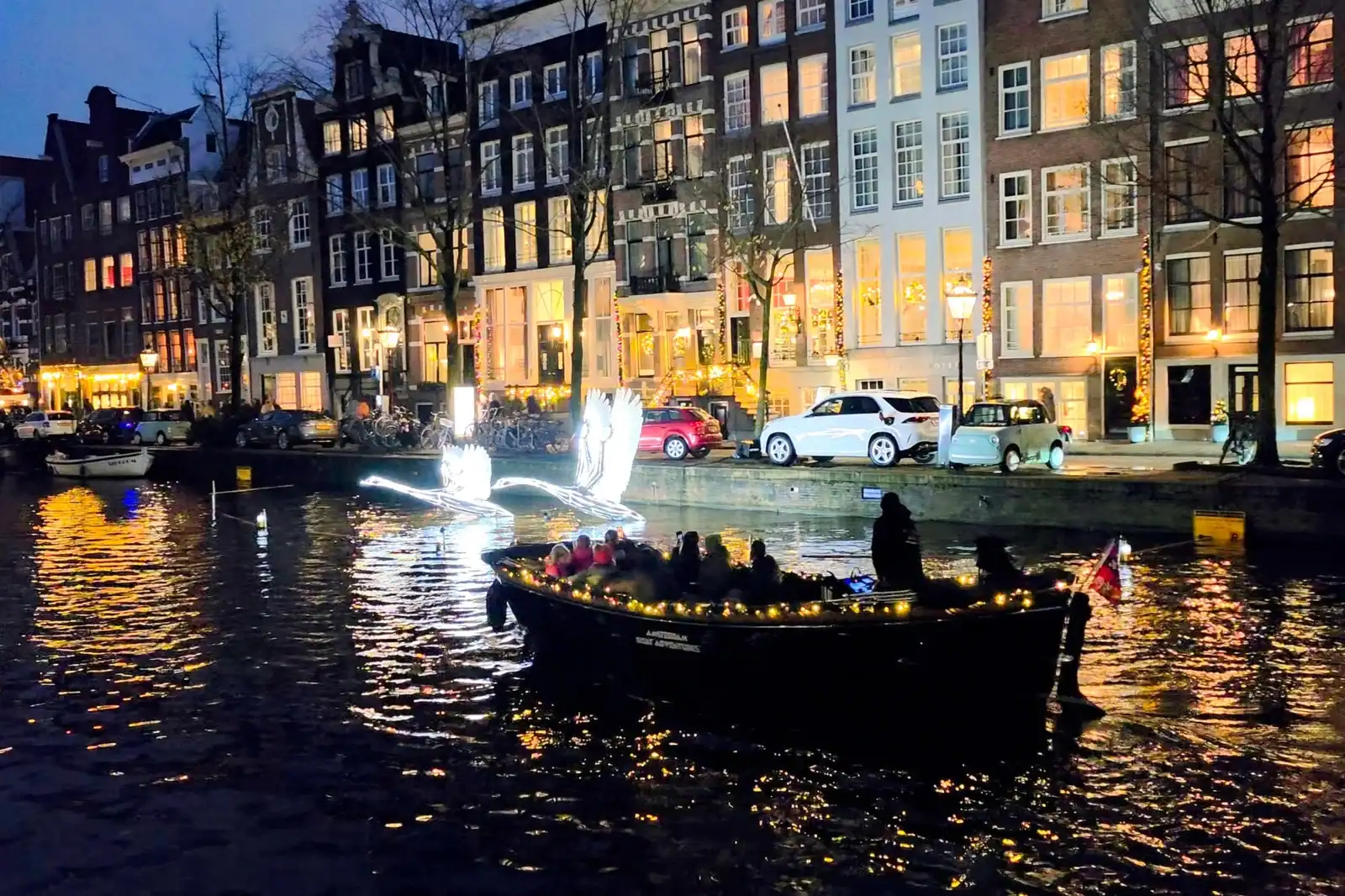 Beautiful evening canal cruise showcasing Amsterdam’s iconic buildings with festive lights.