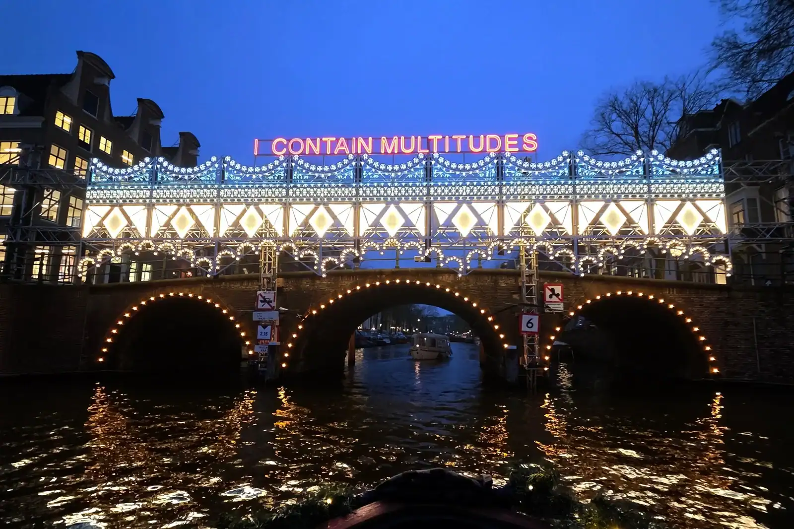 Scenic nighttime boat tour through Amsterdam's canals with iconic lighting displays.