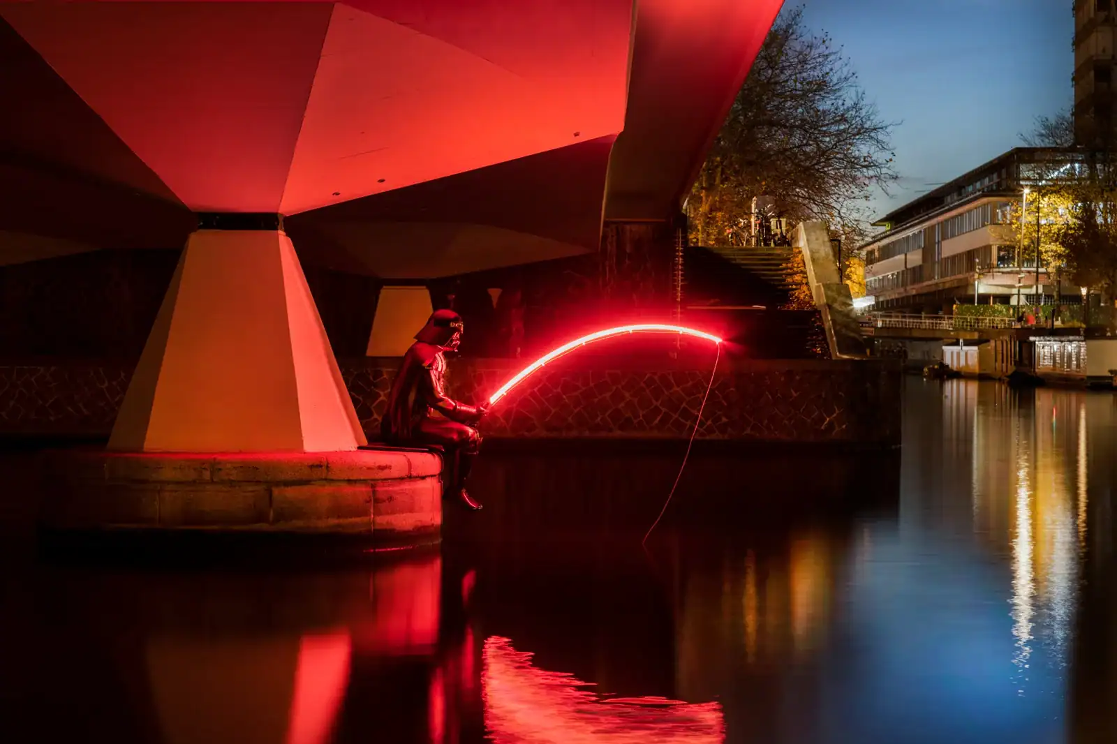 an Light Art work that sits under a bridge by water. It looks like Darth Vader fishing